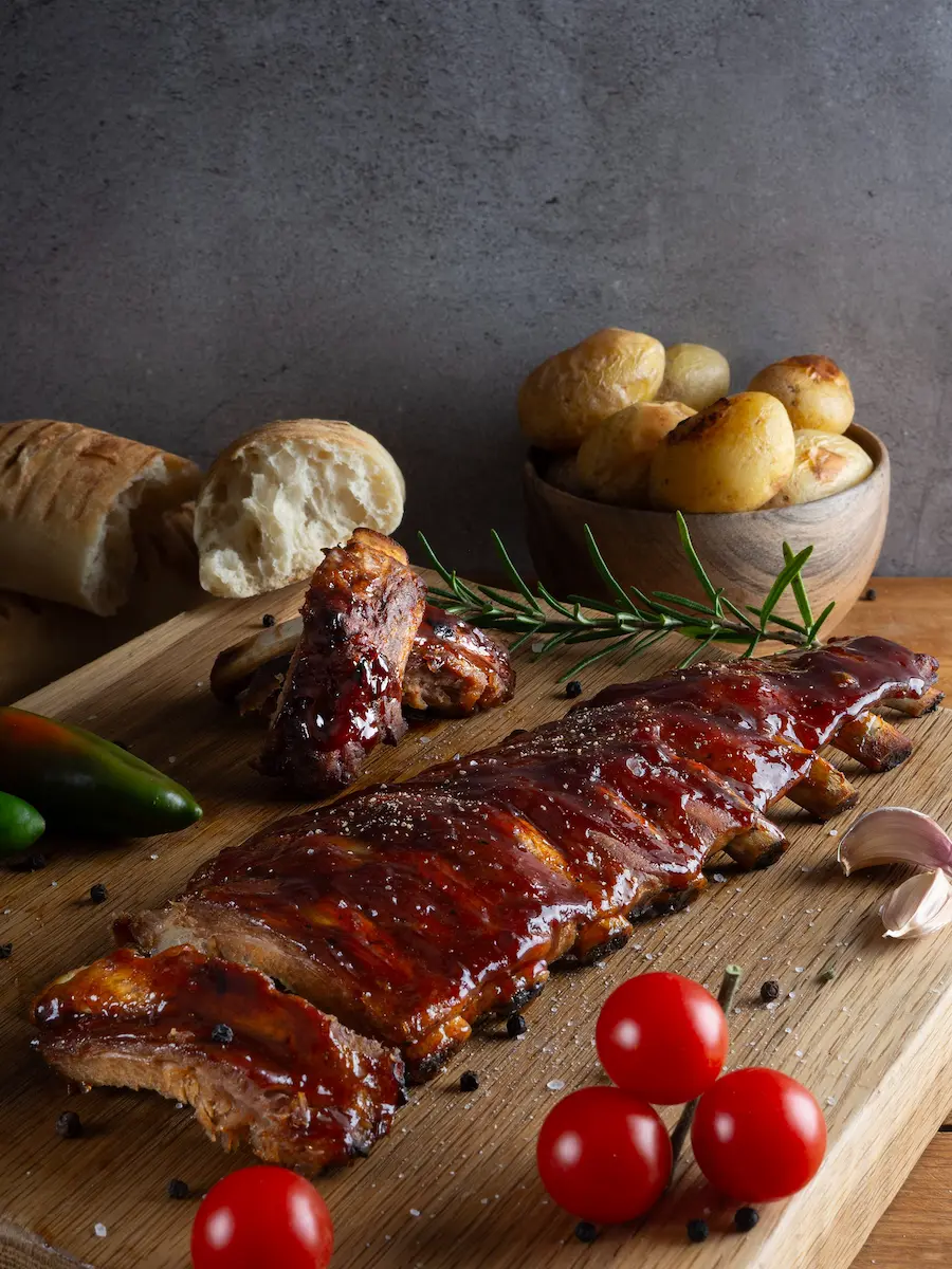 BBQ ribs with roasted potatoes on a wooden cutting board