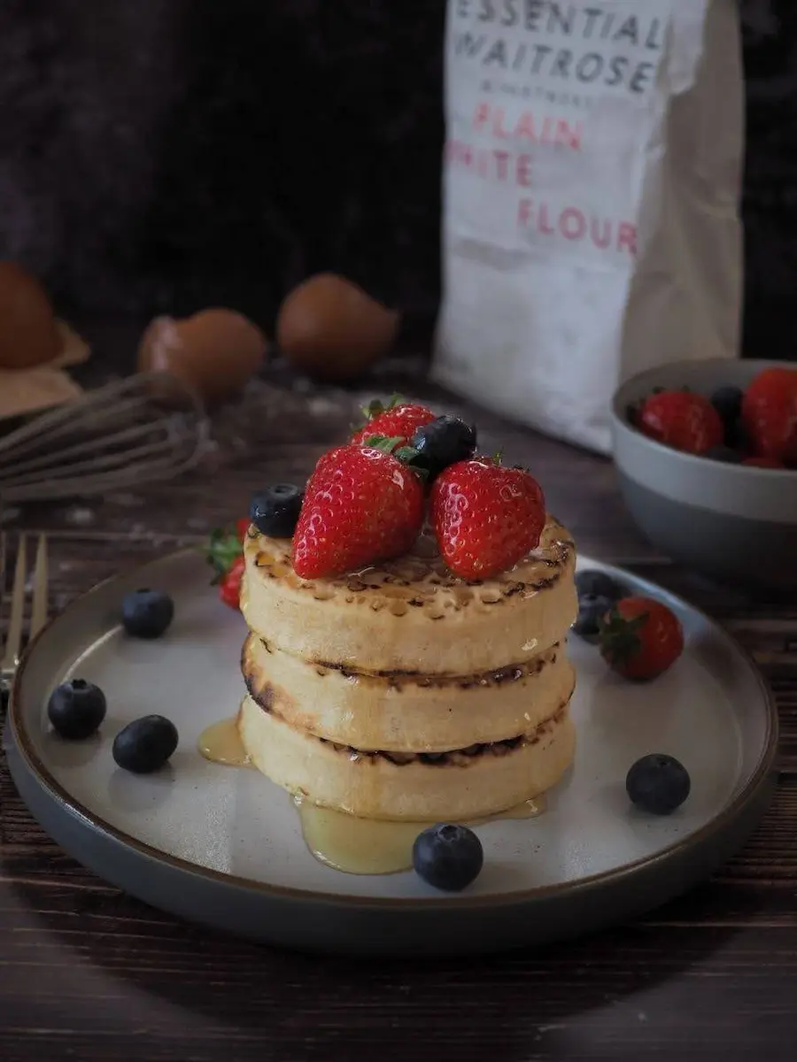 Stack of crepes with butter, strawberries, and smoothie