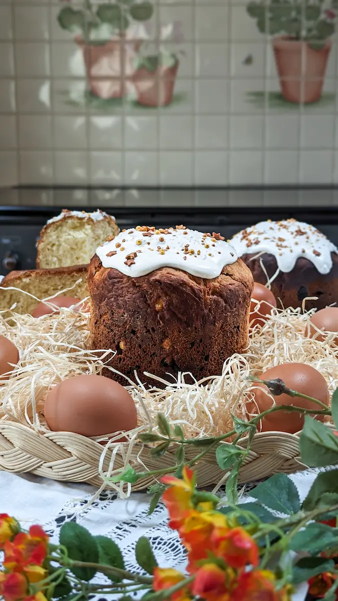 Traditional Easter bread (Kulich) with white icing and sprinkles surrounded by eggs in a woven basket