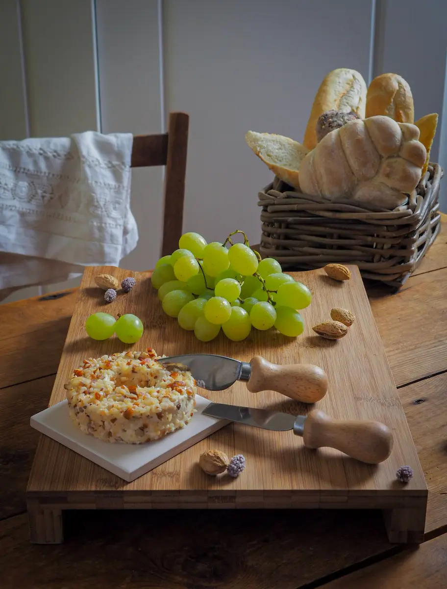 Soft cheese wheel with nuts, grapes, and bread basket