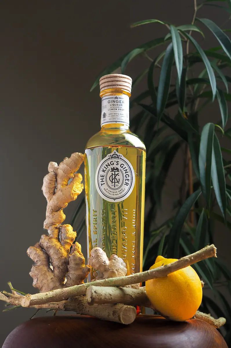 A bottle of The King's Ginger Liqueur posed with large fresh ginger roots