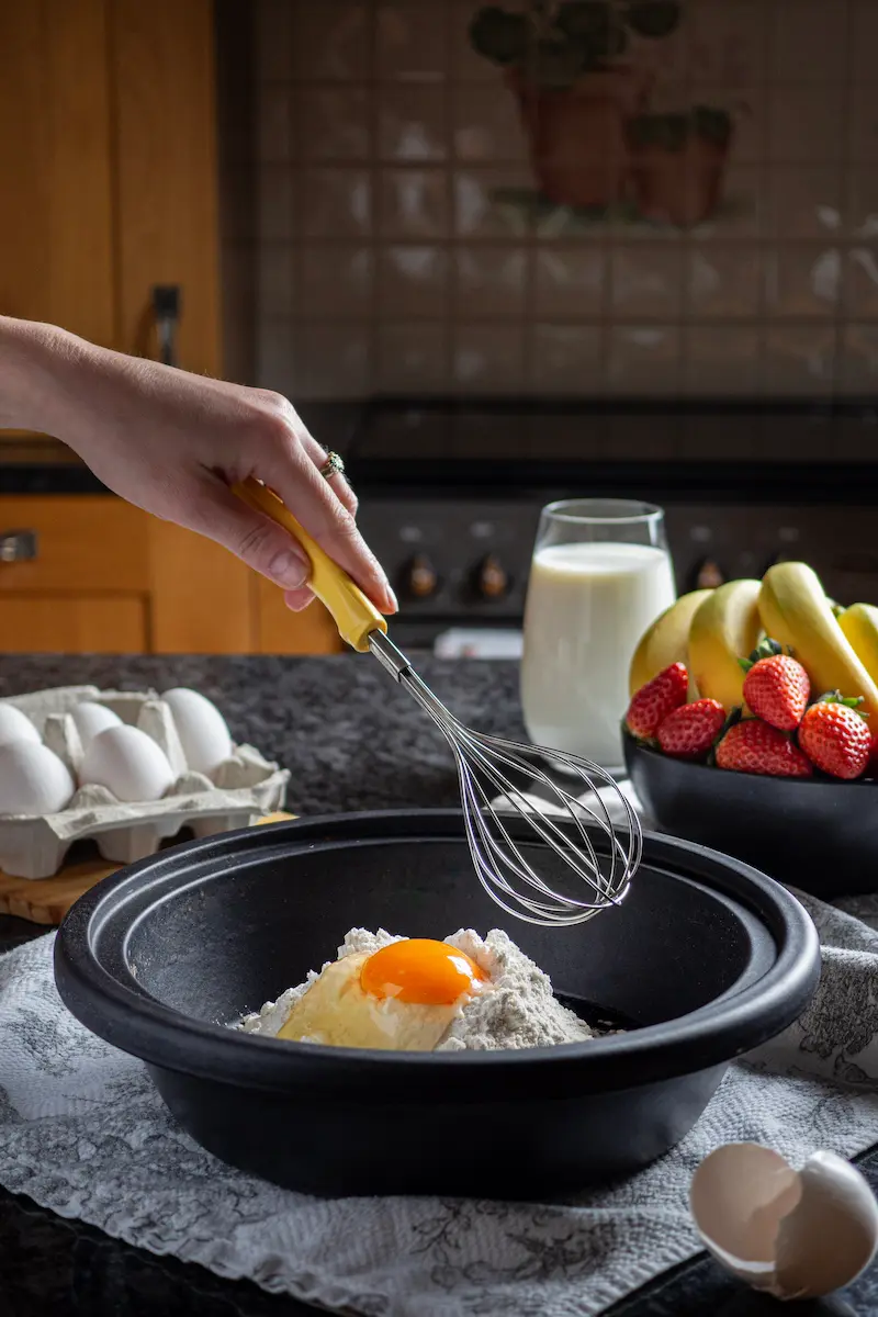 Whisking eggs and flour in a wooden bowl for baking
